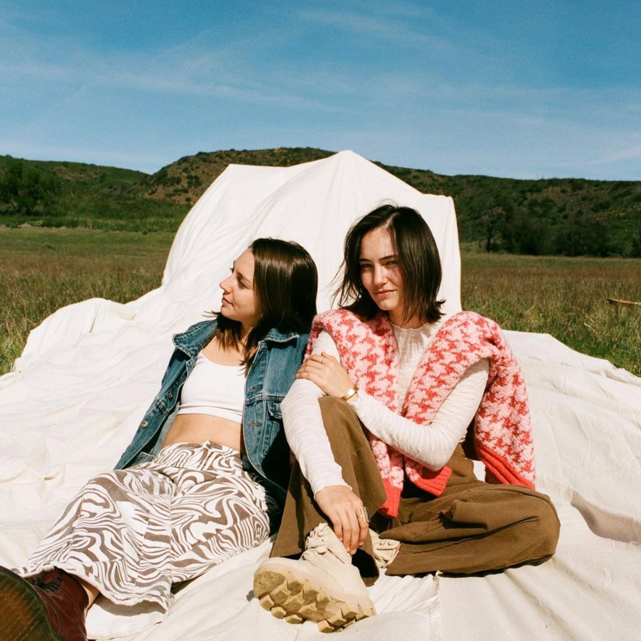 duo OHMA los angeles mia garcia hailey niswanger photo des deux artistes assises par terre sur un drap blanc dans les champs