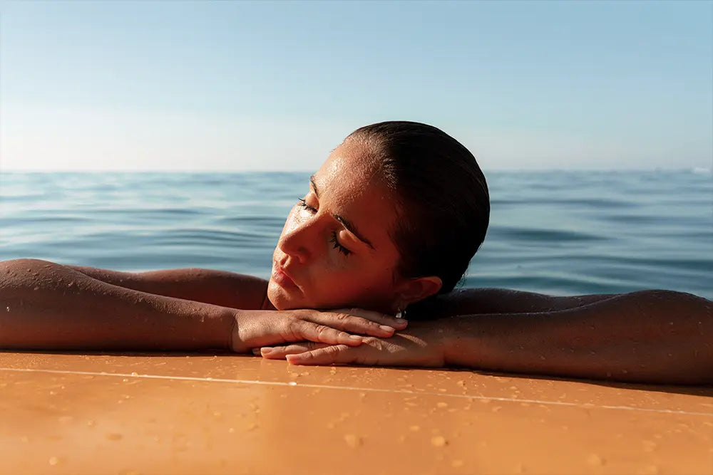femme pose sa tête sur le rebord d'une piscine repos vacances été soleil comment préparer sa peau pour avoir une belle peau tout l'été