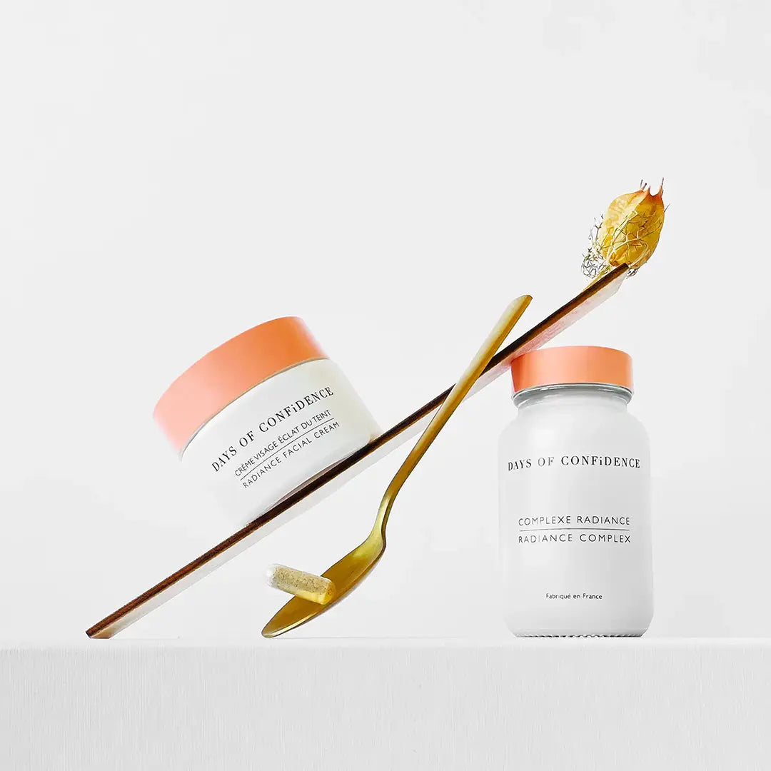 photo packaging routine beauté bien etre holistique radiance sur fond blanc packaging blanc et rose compléments alimentaires naturels soutiennent une planche et crème hydratante visage éclat du teint posée sur la planche et cuillère couleur or qui tient une gélule