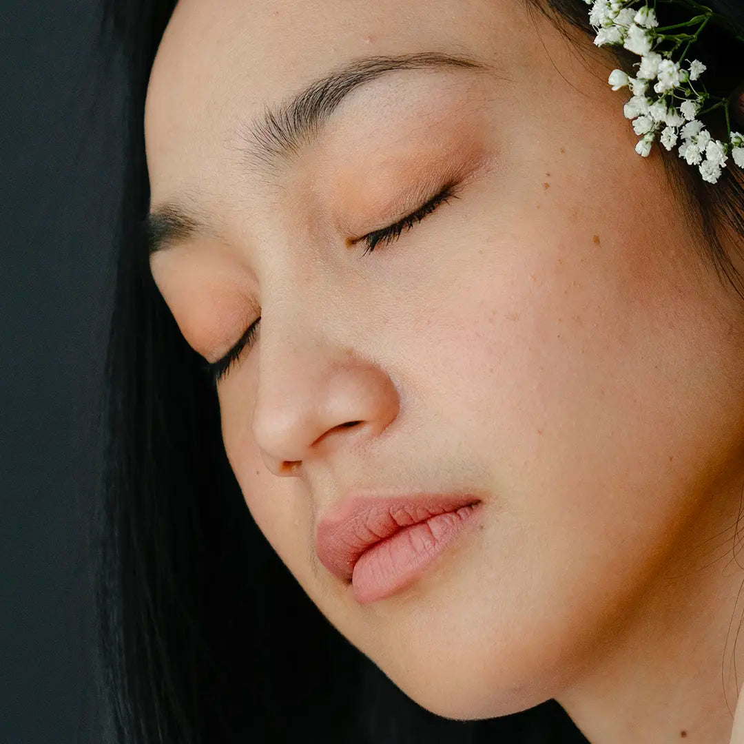 femme yeux fermés naturelle fleurs blanches dans les cheveux peau sensible rougeurs la routine idéal pour les peaux sensibles et reactives