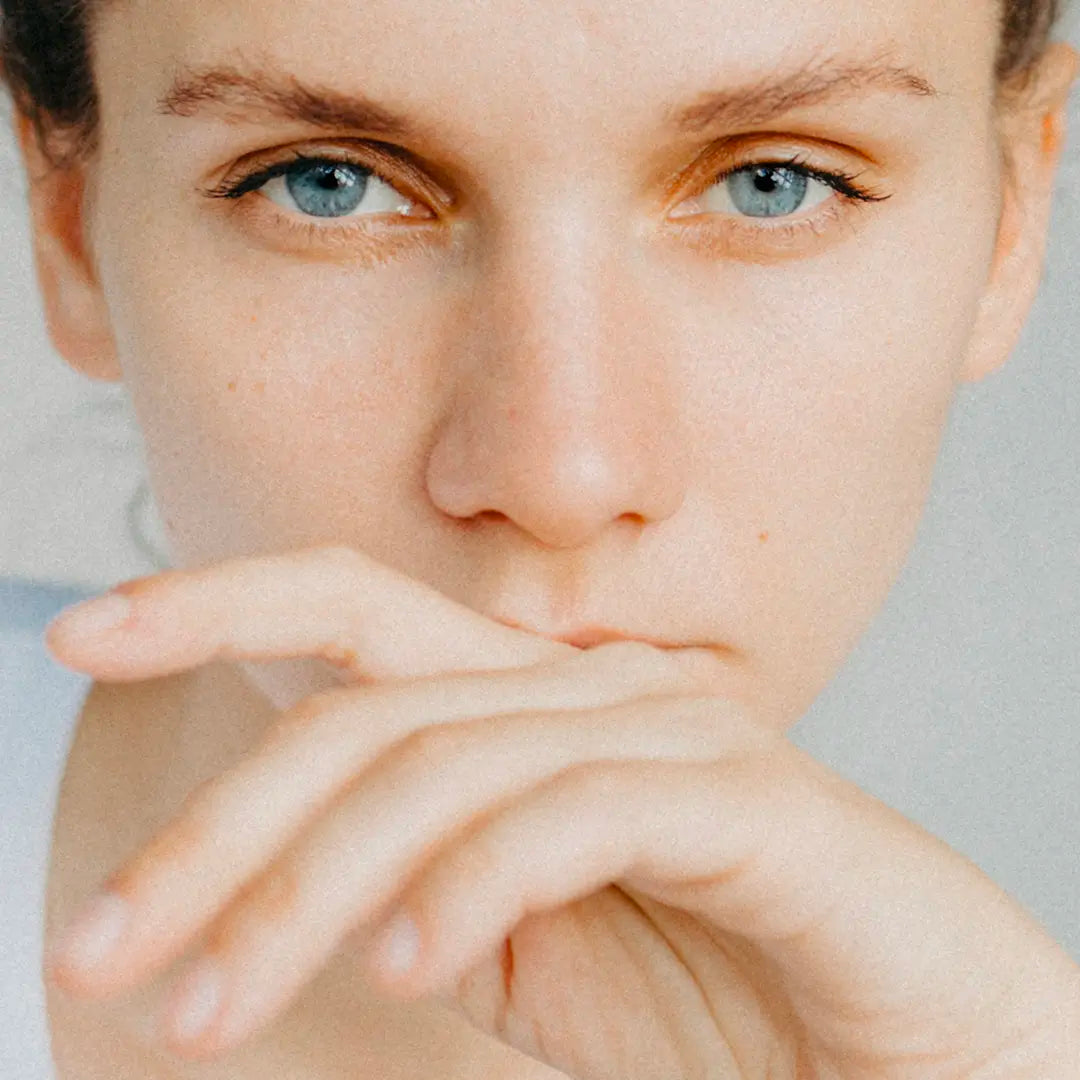 femme yeux bleues regard et teint fatigués mains devant la bouche besoin d'une routine anti stress et sommeil